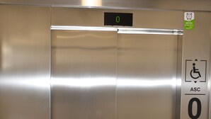En elevator med digitalt display, et tilgængelighedssymbol og en mærkat, der angiver non-stop service.