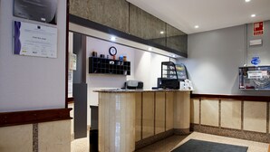 A reception area with a marble counter, a clock, a shelf with various items, and a Wi-Fi sign. - Hotel San Jorge (Santurtzi)