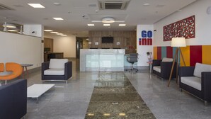 Una hall moderna con aree relax, una reception e una cucina sullo sfondo.