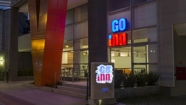 Un edificio moderno con un evidente cartello 'GO inn', un ingresso coperto e un pannello luminoso digitale.