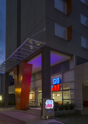 A modern building with a prominent 'GO inn' sign, a covered entrance, and a digital display board.