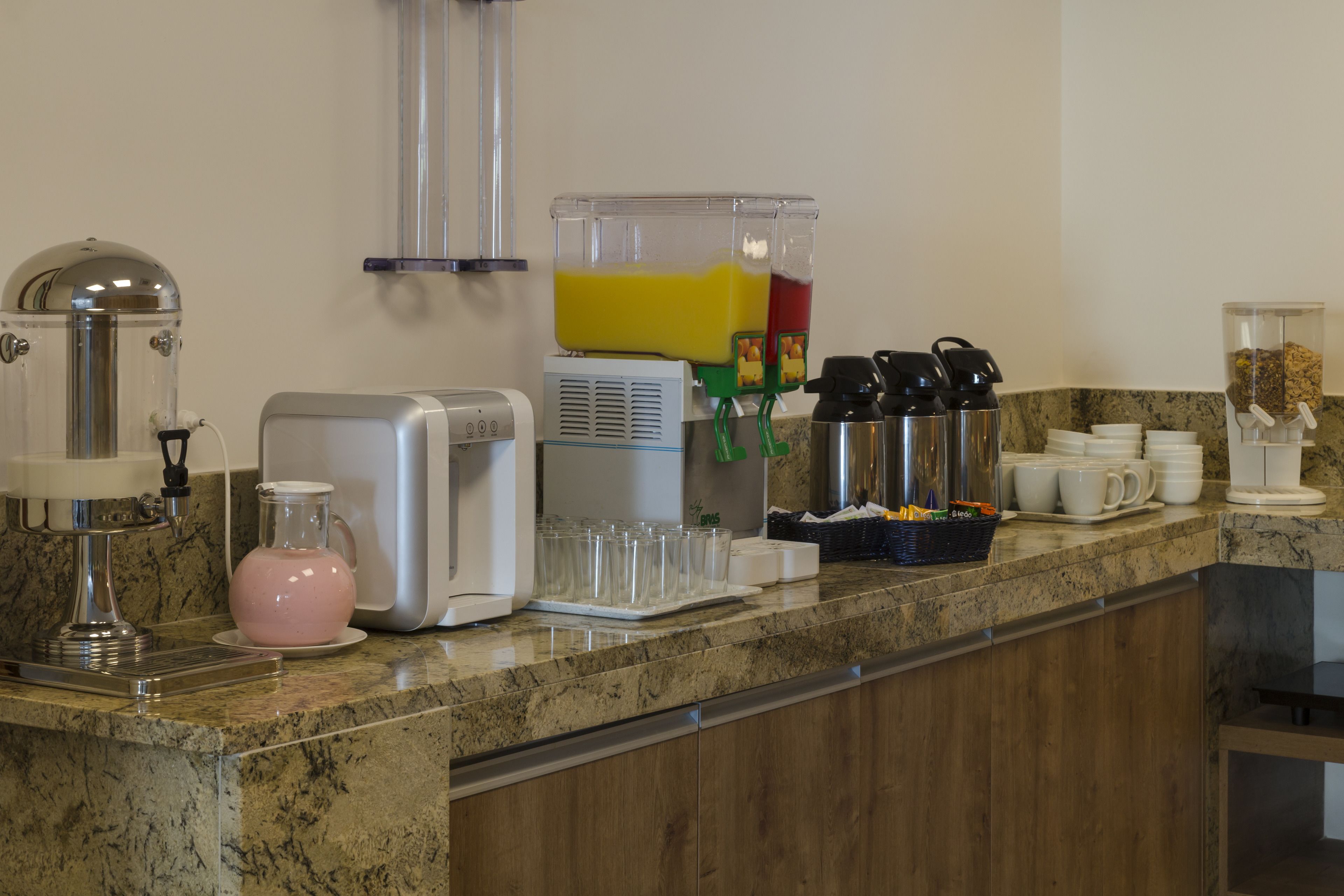 A kitchen area with a coffee machine, a juice dispenser, and various kitchen utensils.