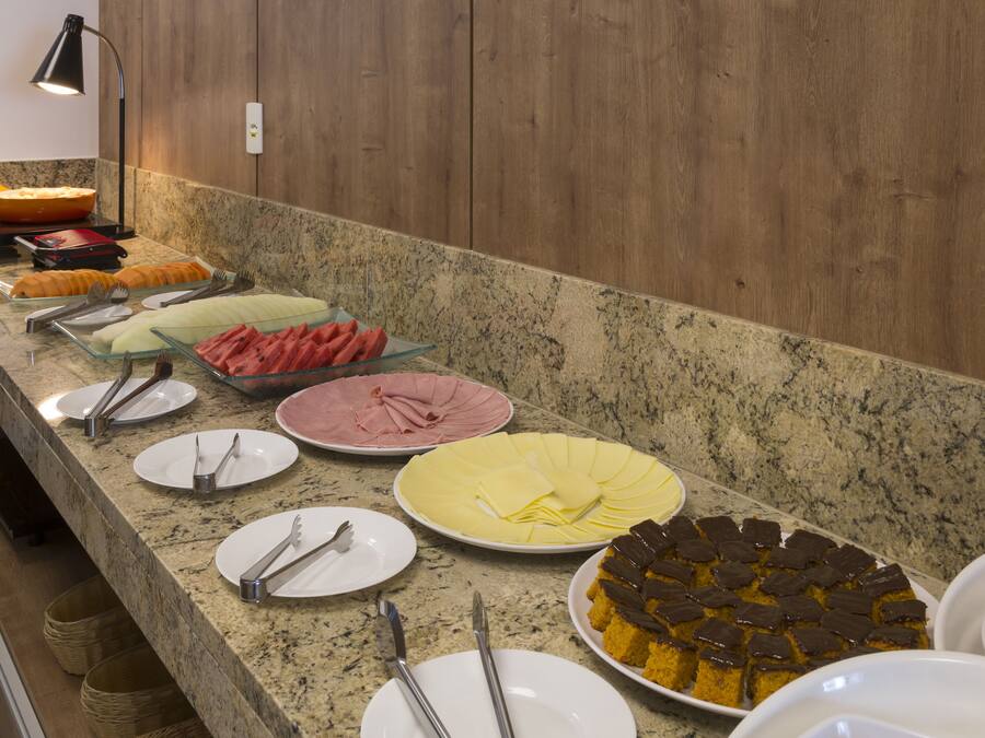 Disposición de buffet con diversos alimentos y utensilios sobre una encimera de granito.