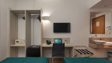 Habitación de hotel con dos camas, un escritorio con computadora, televisión, microondas, teléfono y lavamanos.