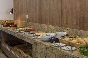 Una barra de buffet con diversos alimentos y utensilios para servir sobre una encimera de mármol.