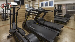 Una palestra con tapis roulant, ellittiche e un muro di specchi.