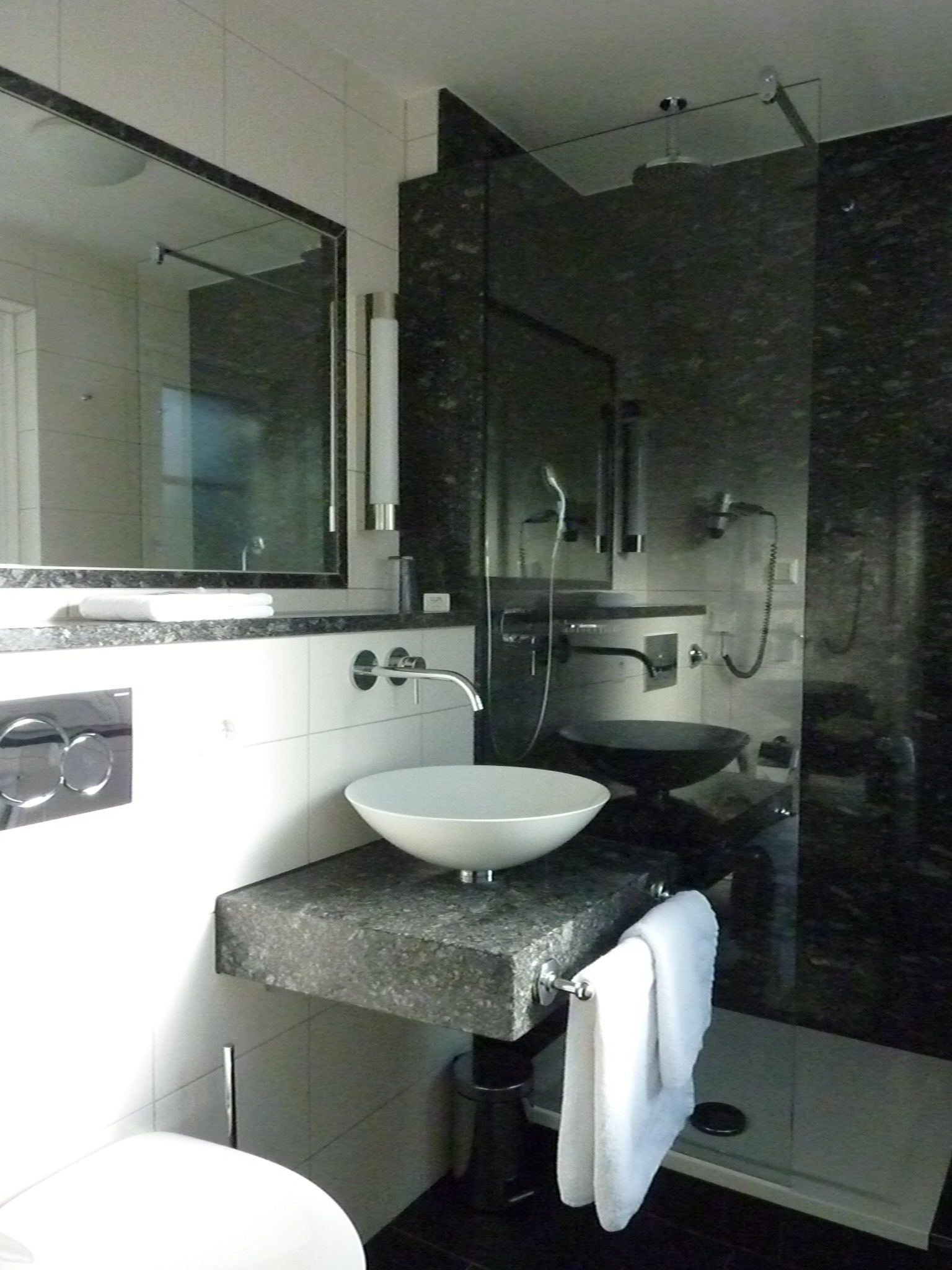 A modern bathroom with a white vessel sink, a large mirror, and a glass-enclosed shower area.