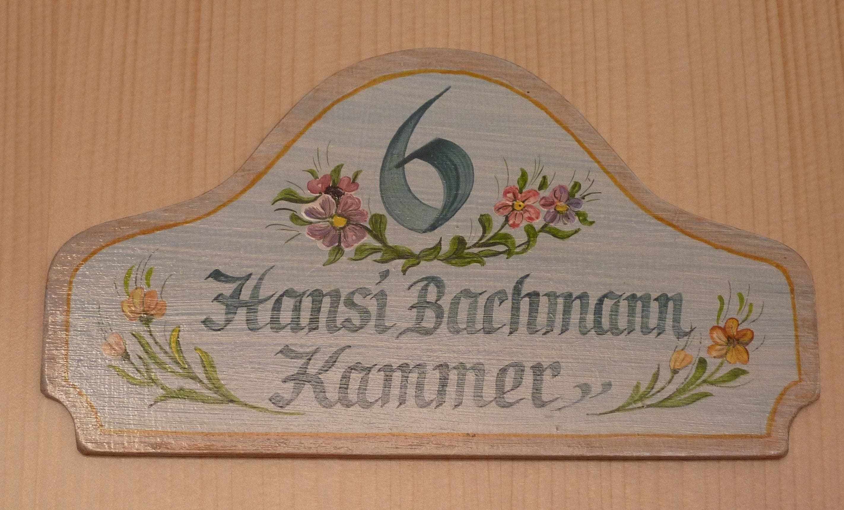 A wooden sign with the number 6 and the name "Hansi Bachmann" along with "Kammer".