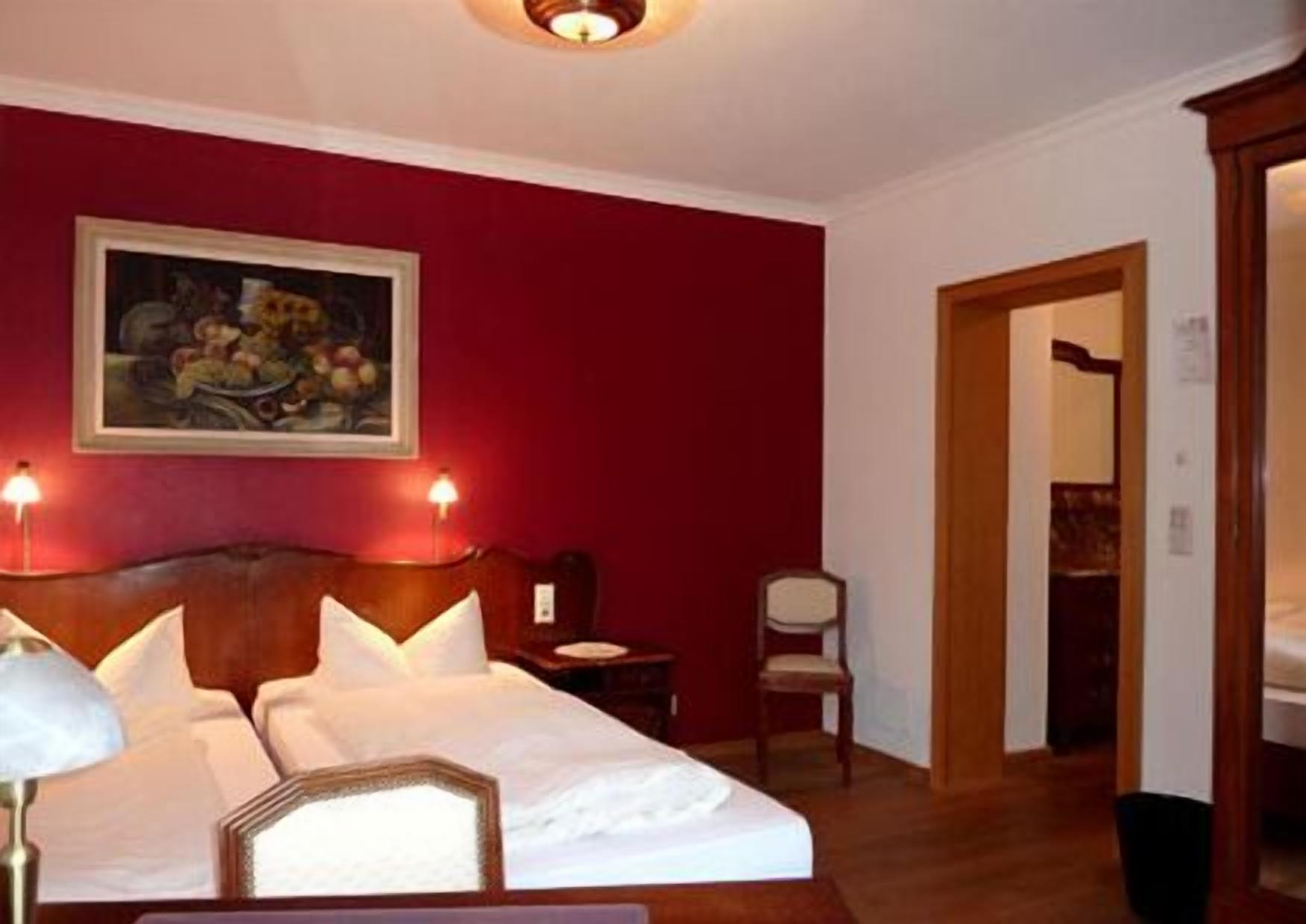 A hotel room with a large bed, two bedside tables, a nightstand, a chair, and a painting on the wall.