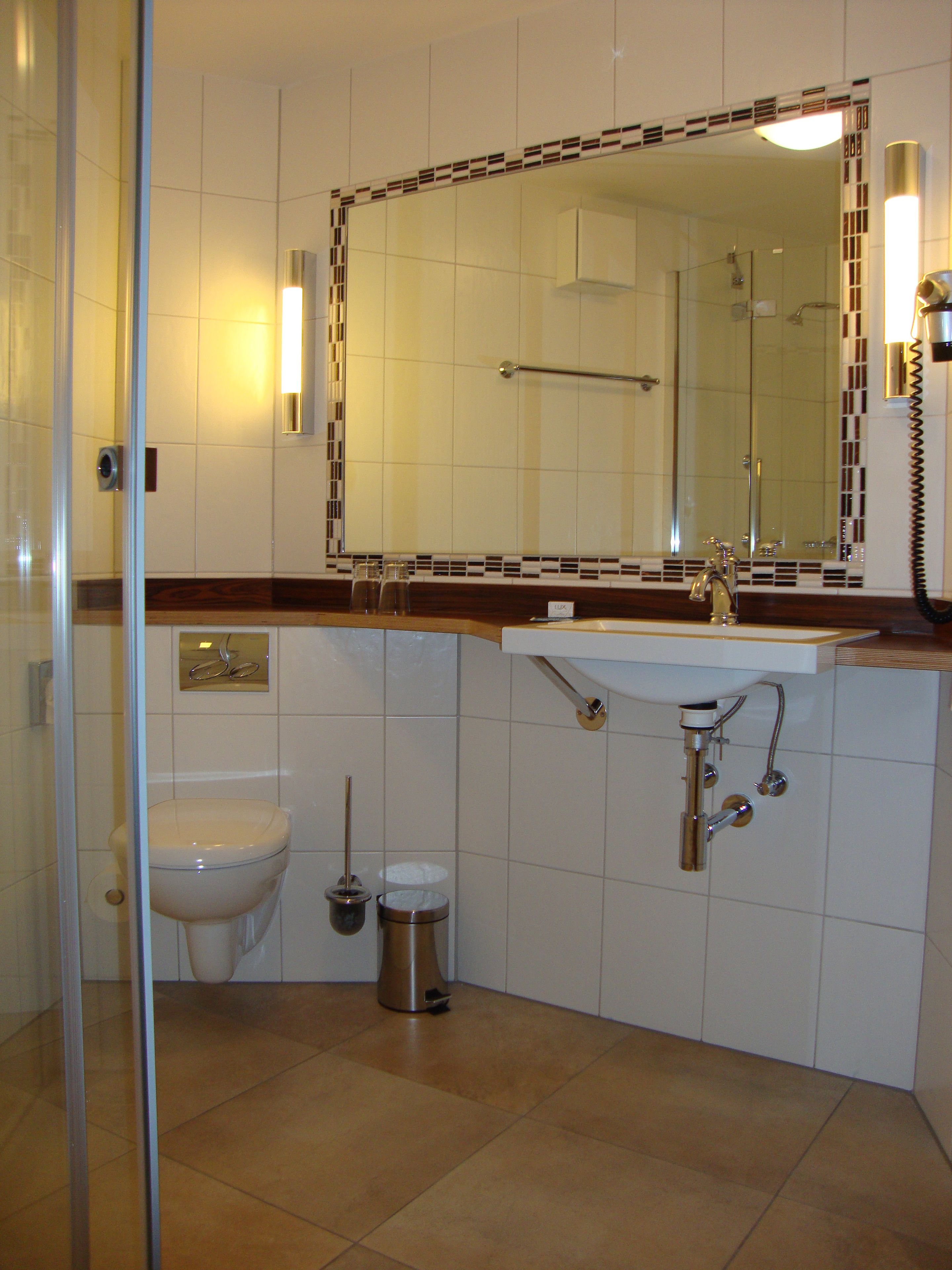 A bathroom with a toilet, bidet, sink, and a glass shower enclosure.