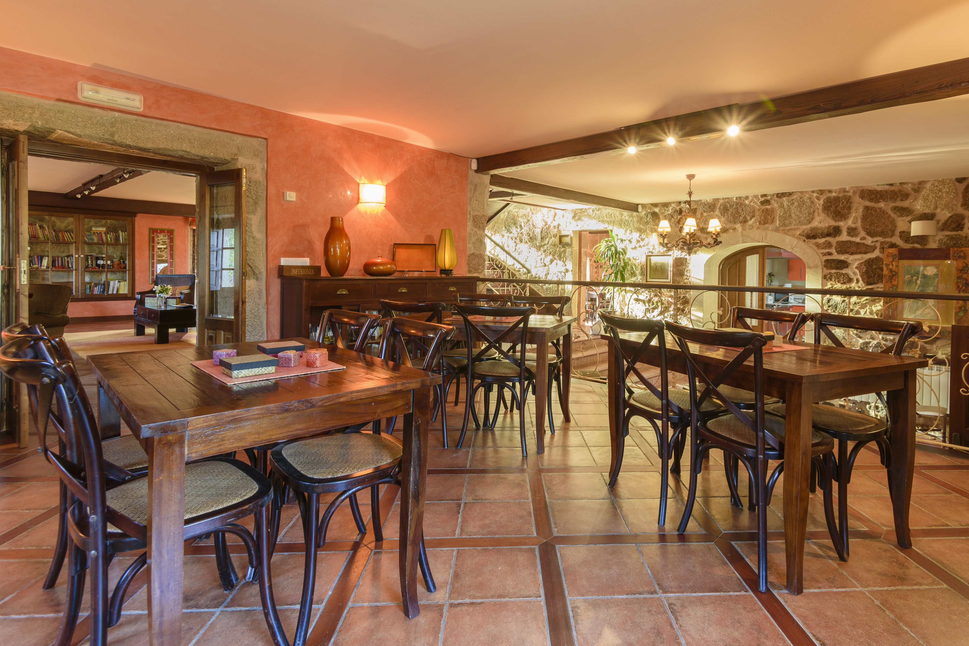 Un comedor con mesa y sillas de madera, una estantería y una pared de piedra.