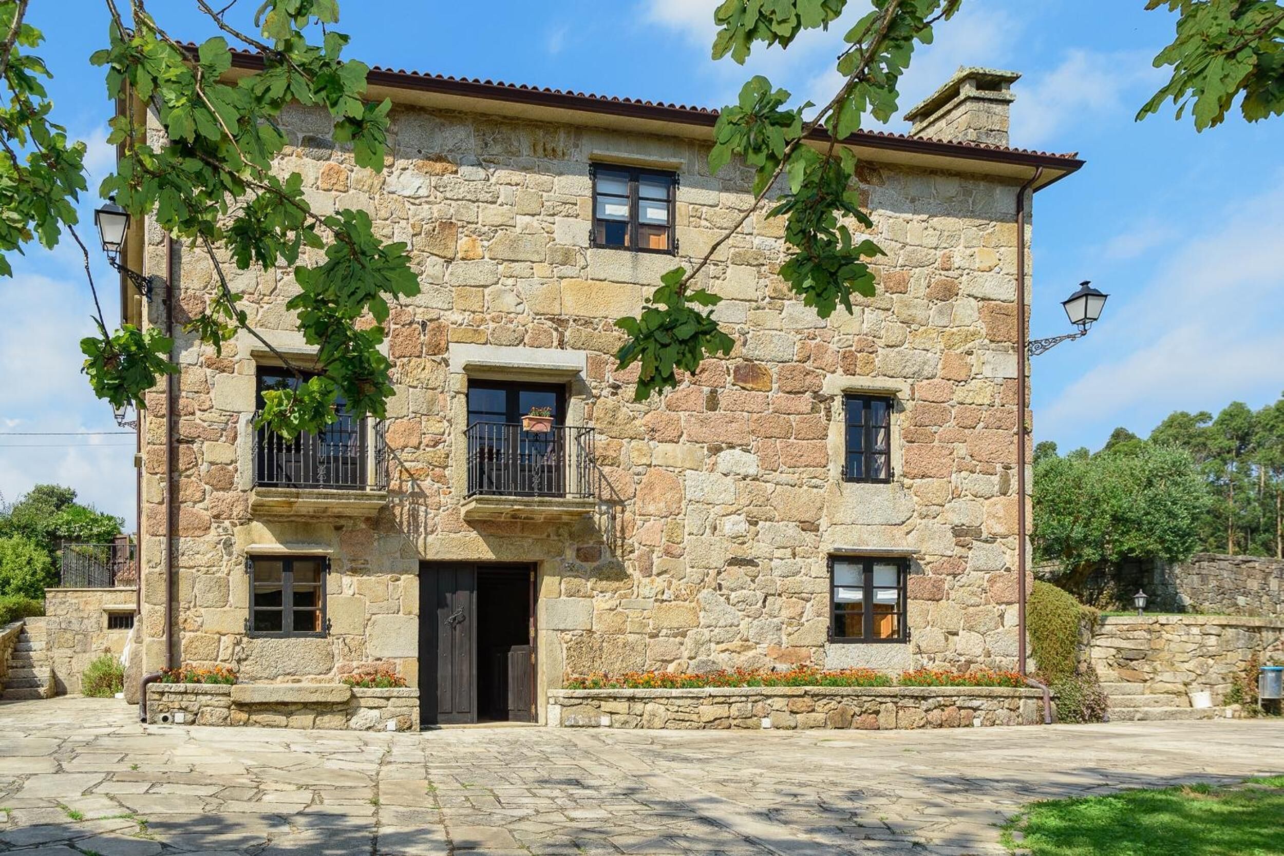 Un bâtiment en pierre à l’architecture traditionnelle, doté d’une entrée centrale, de deux balcons et d’un petit porche.