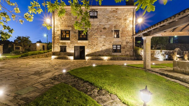 A stone building with a courtyard, illuminated by street lamps. - Casal dos Celenis (Caldas de Reis)