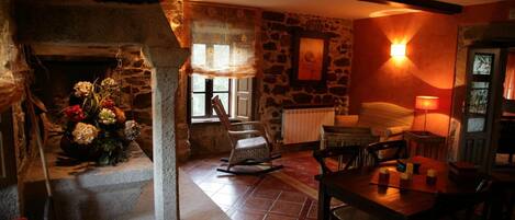 A cozy room with a stone fireplace, a wooden table, and a comfortable seating area.
