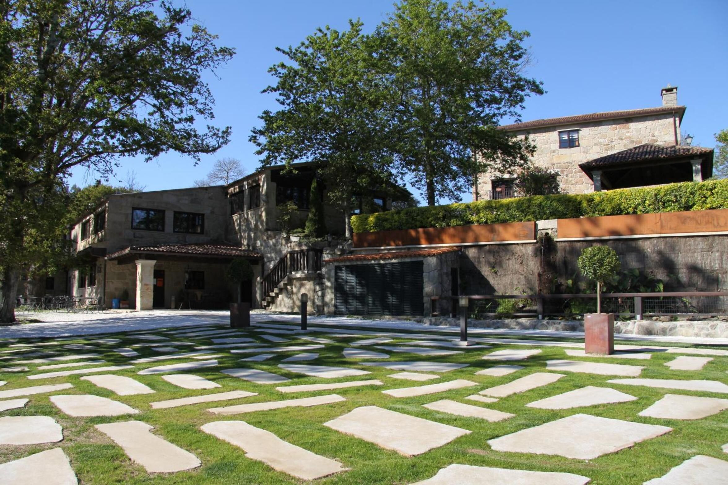 Un patio con senderos de piedra, un edificio de piedra y un árbol.
