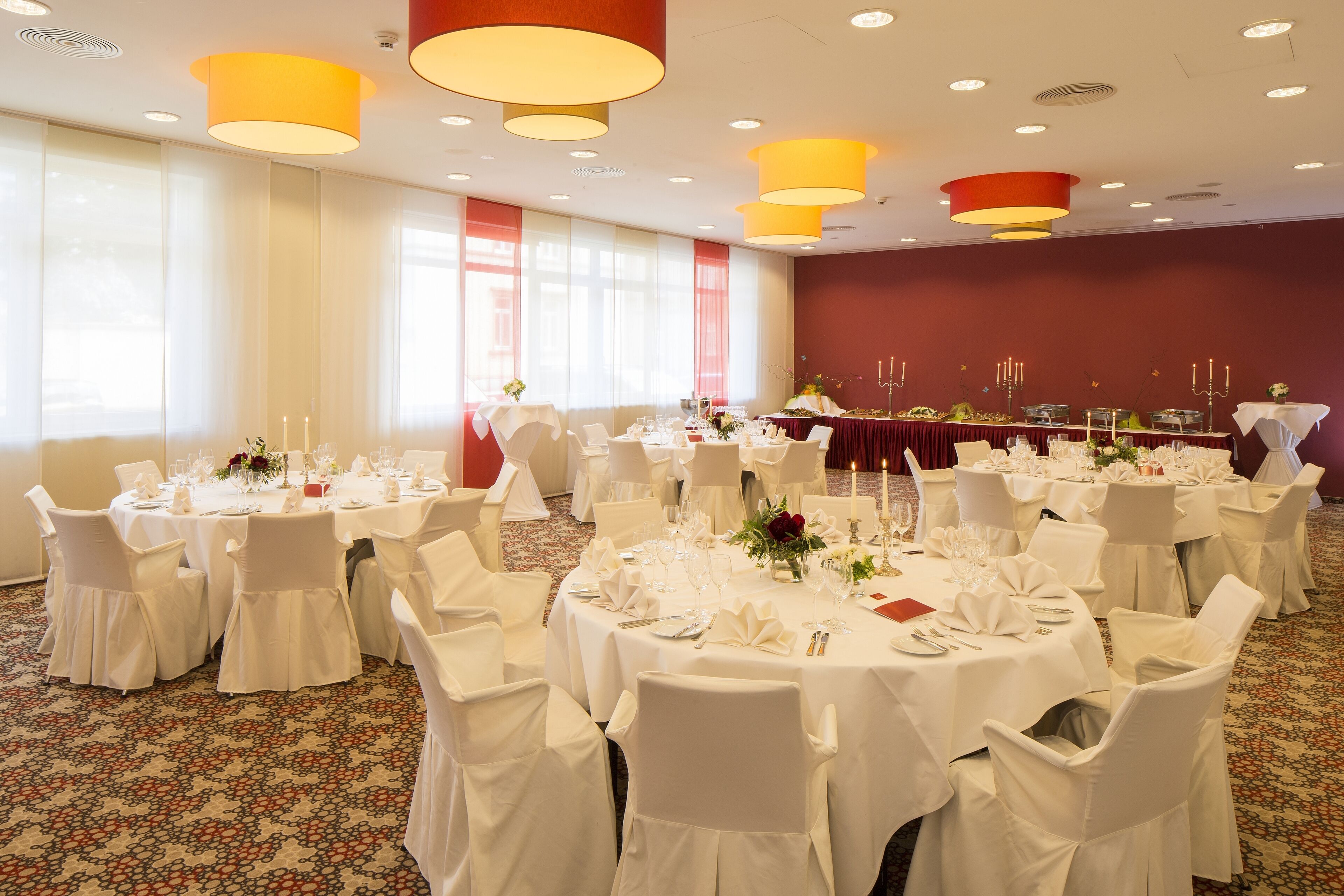A banquet hall with round tables set for a formal event, featuring white tablecloths, chairs, and floral centerpieces.