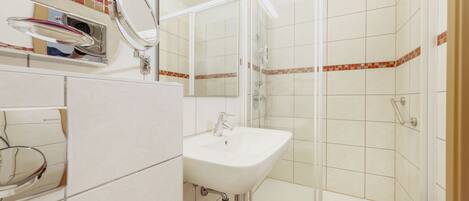 Un baño con lavabo, espejo y ducha.