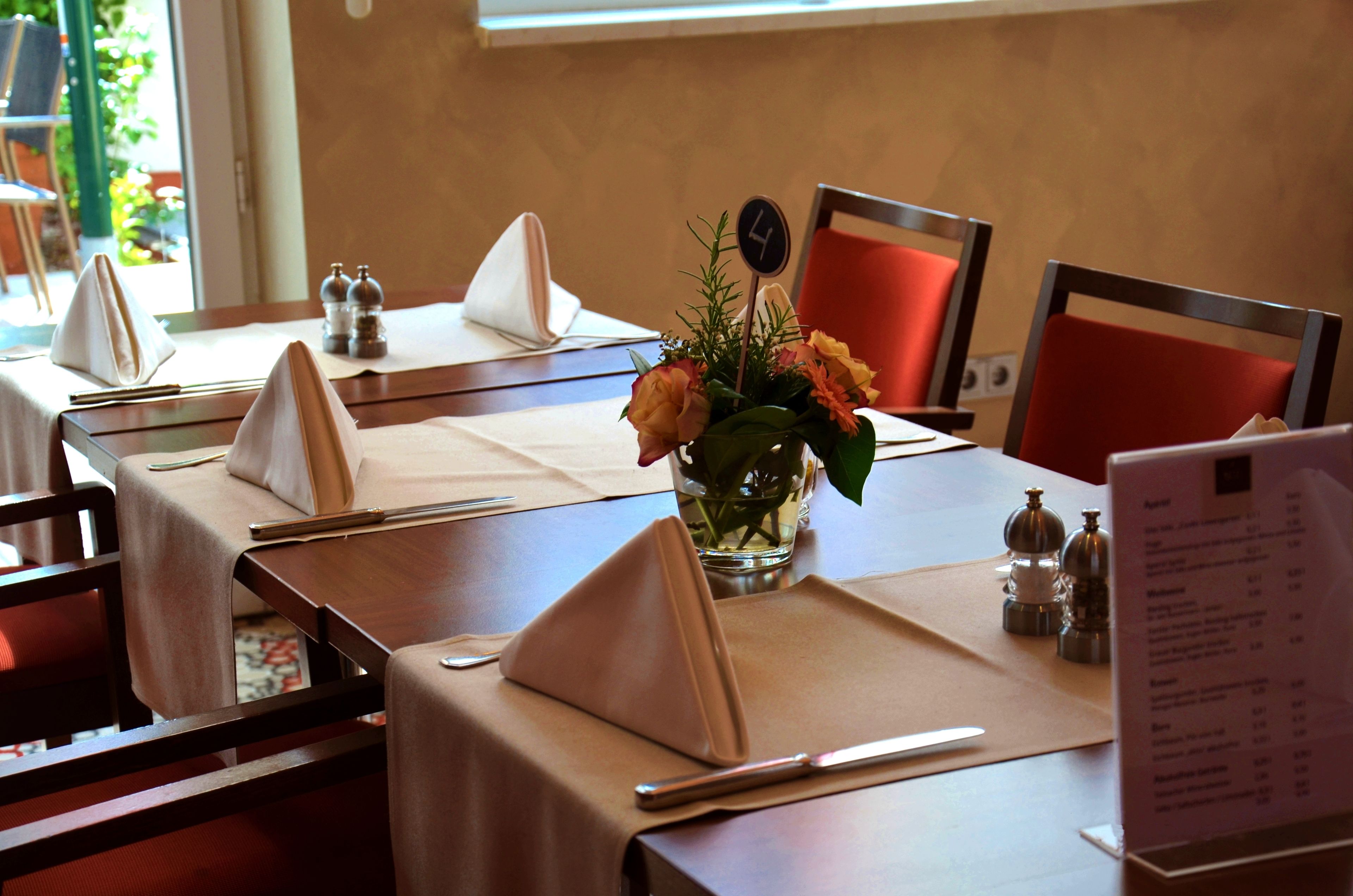 A dining table set with a vase of flowers, salt and pepper shakers, a clock, and a menu.