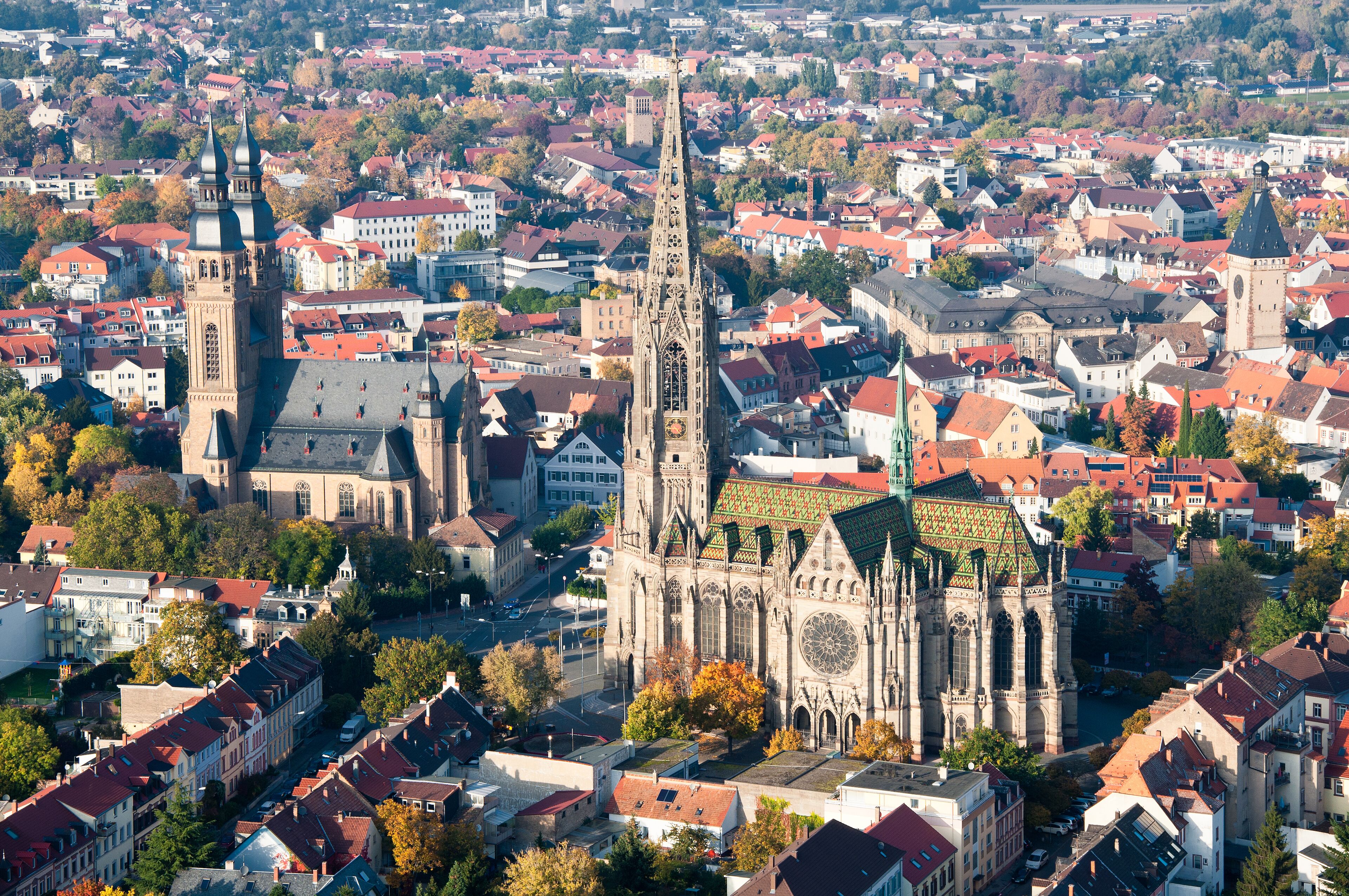Eine historische Kathedrale mit einem hohen Turm und einem Glockenturm, umgeben von traditionellen Gebäuden mit roten Dächern.