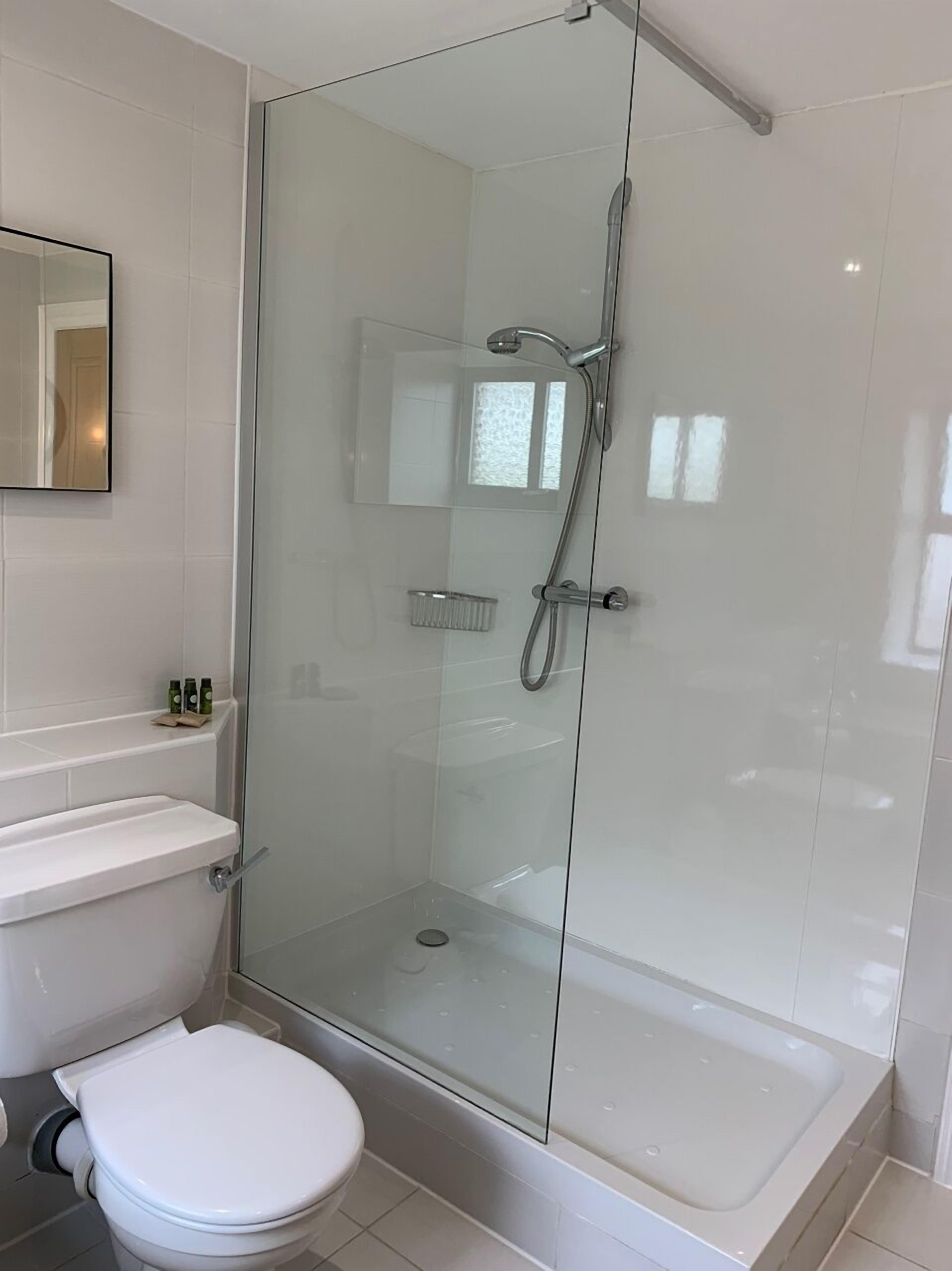 A modern bathroom with a glass-enclosed shower, a toilet, and a sink.