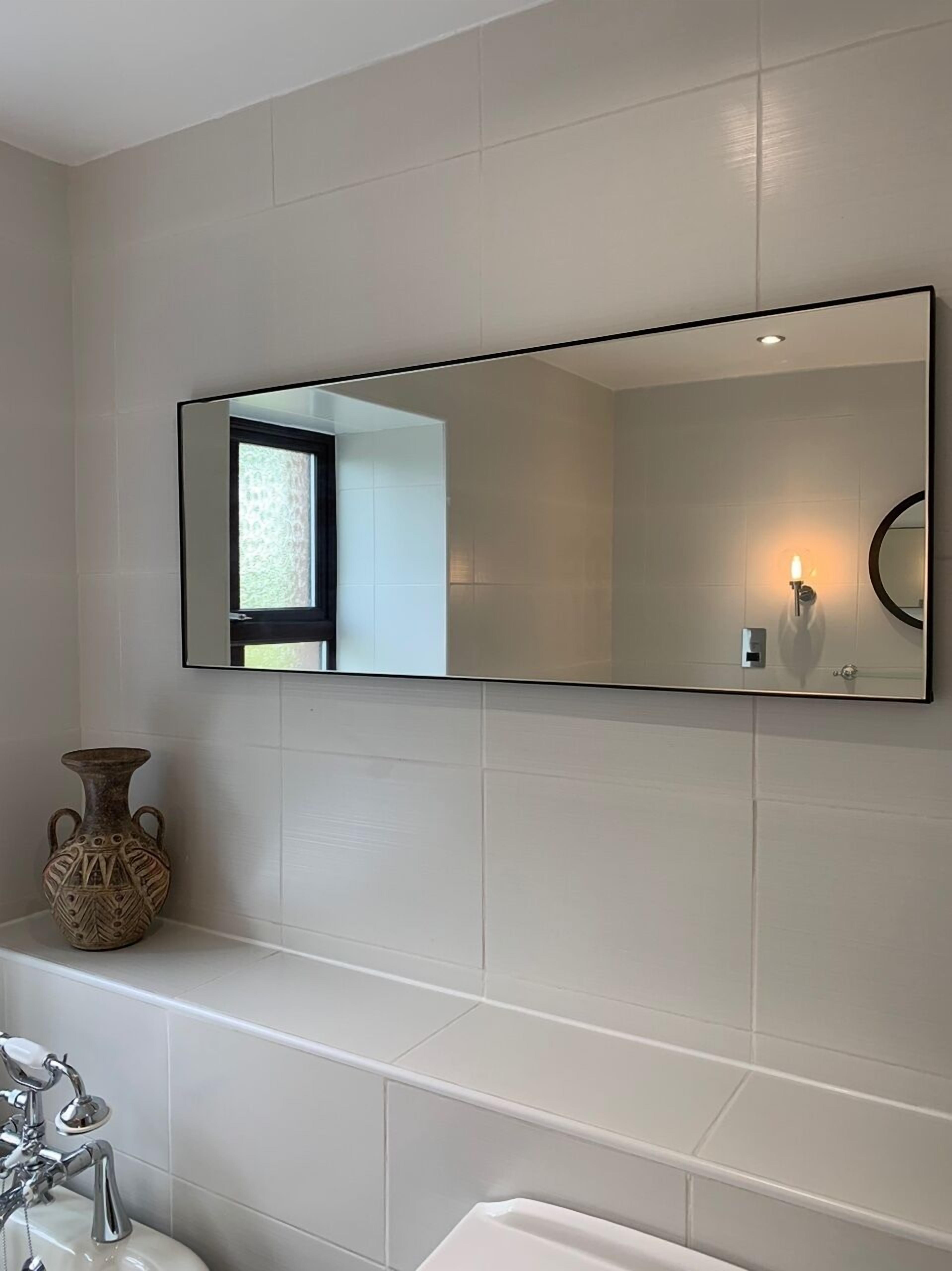 Une salle de bain avec un grand miroir, un vase et une baignoire.