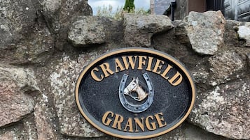 A stone wall with a plaque that reads "Crawfield Grange" and a horse's head emblem.