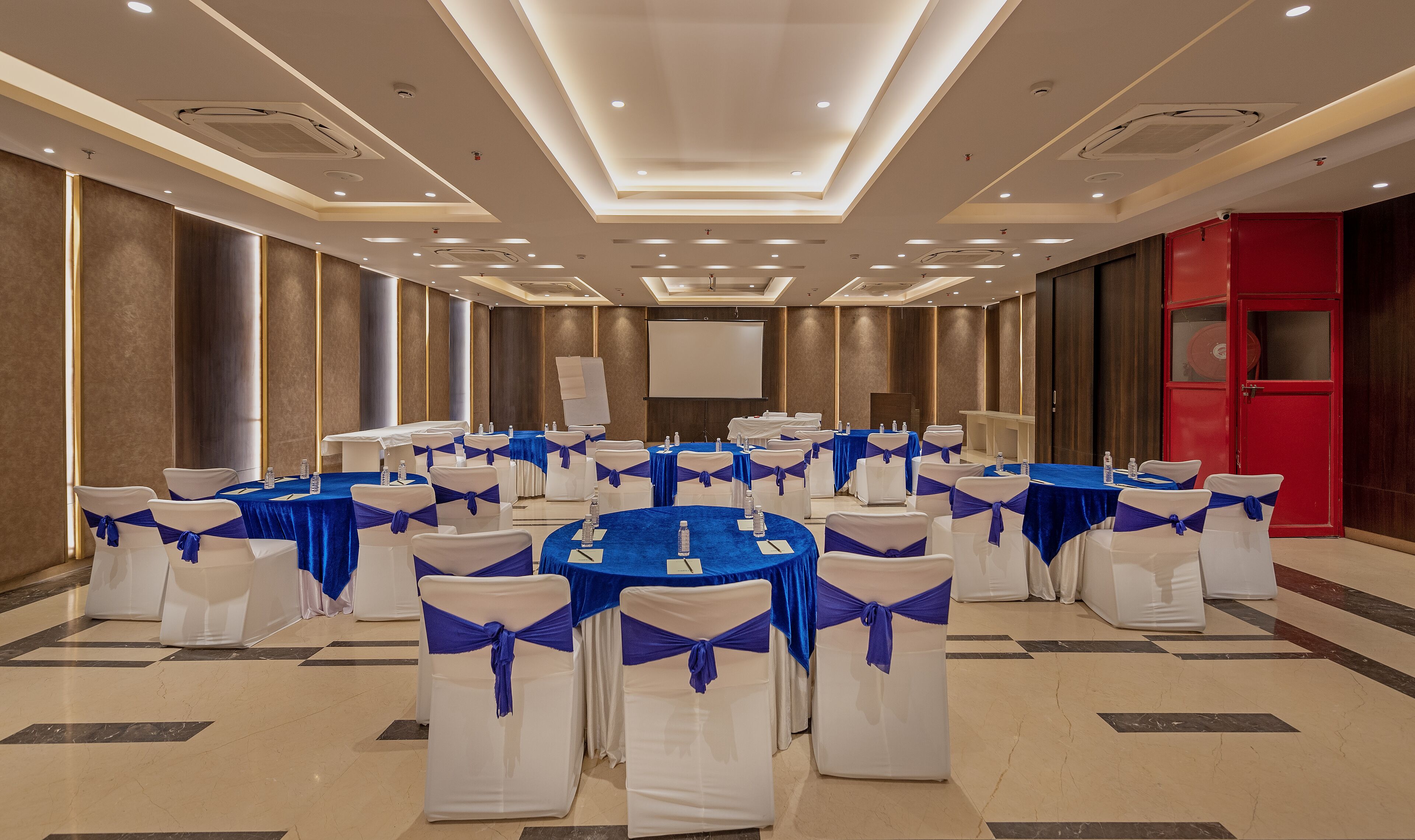 Une salle de conférence avec des tables rondes, des chaises blanches et des bandeaux bleus.