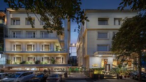 A multi-story hotel with a modern facade, balconies with plants, and a well-lit entrance. - Hotel Saket 27 (New Delhi)
