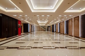 A long, well-lit hallway with a reflective floor and a central staircase. - Hotel Saket 27 (New Delhi)