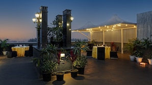 An outdoor dining area with tables, chairs, and potted plants. - Hotel Saket 27 (New Delhi)