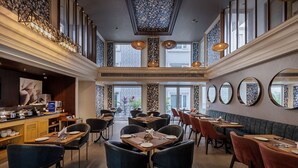 A spacious restaurant with high ceilings, large windows, and a variety of seating options including tables and booths. - Hotel Saket 27 (New Delhi)