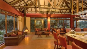 A cozy interior with a fireplace, leather sofas, and a dining area with a bar. - Mara Leisure Camp (Maasai Mara)