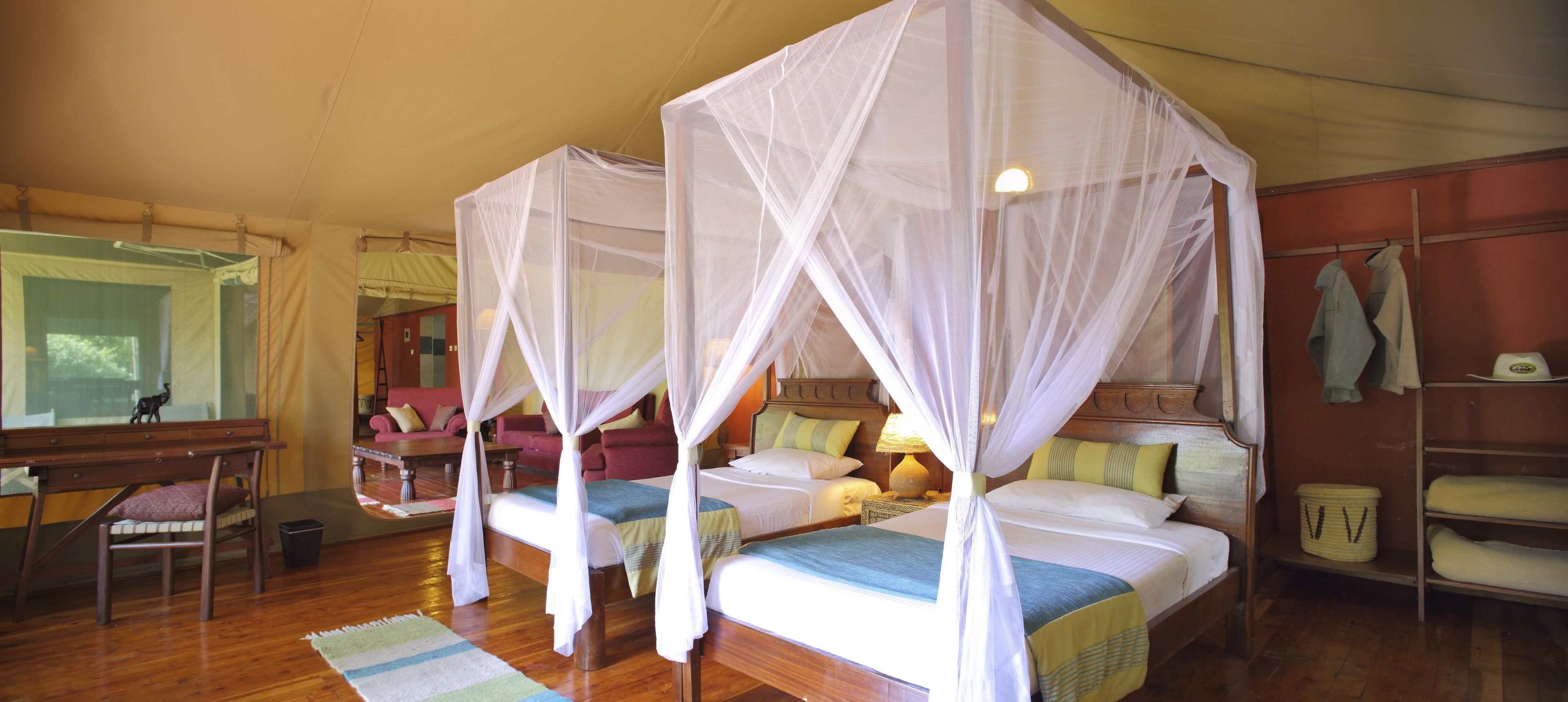 Una habitación con dos camas, cada una con dosel, muebles de madera y vistas al exterior.