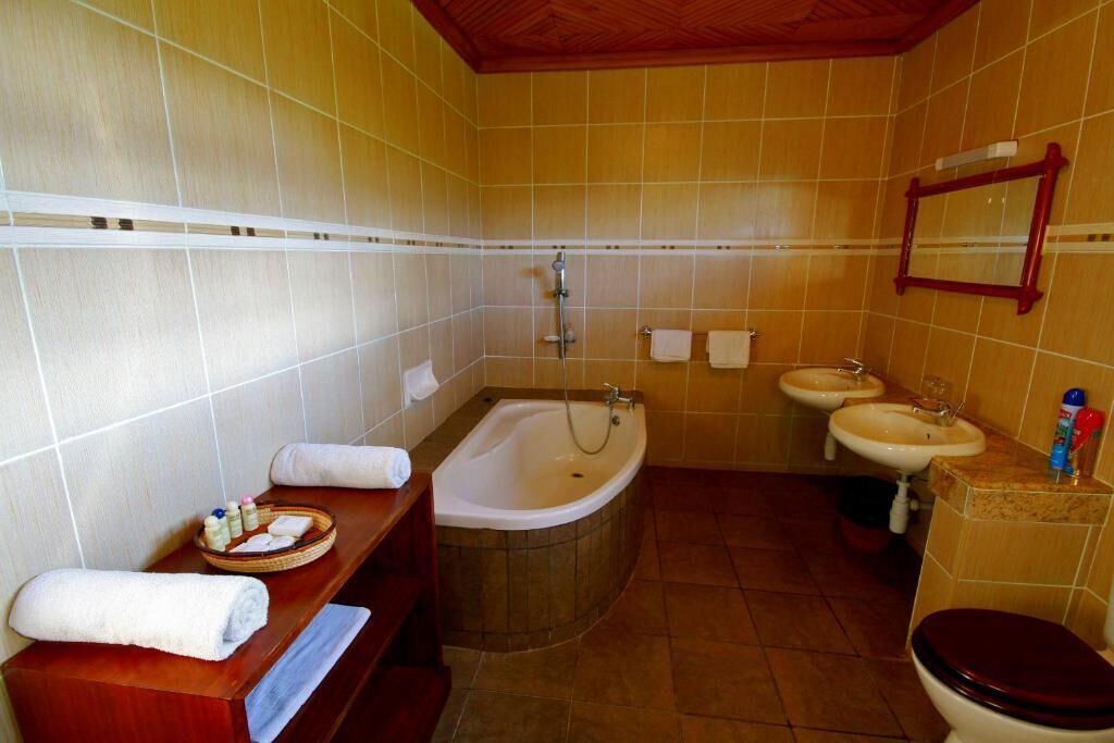 A bathroom with a bathtub, two sinks, a toilet, and a vanity with towels and toiletries.