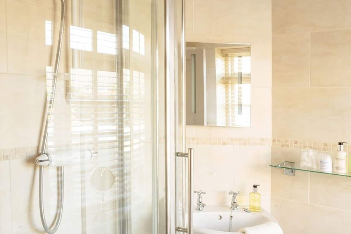 A modern bathroom with a glass-enclosed shower, a white sink, and a mirror above it.