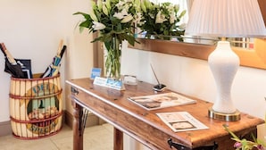 Una scrivania di legno con un vaso di fiori, una lampada e un cesto di chiavi.
