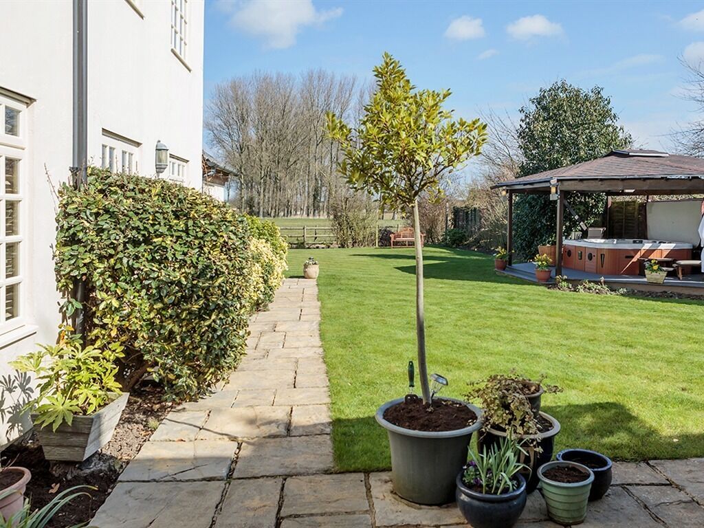 A well-maintained garden with a paved pathway, a small tree, and potted plants.