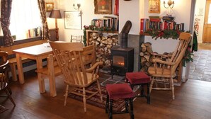 A cozy living room with a fireplace, wooden furniture, and bookshelves. - The Sun Inn (Ellesmere)
