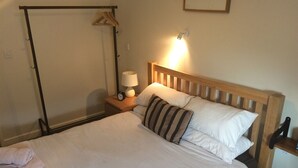 A neatly made bed with white linens and striped pillows, a bedside lamp, and a wooden headboard. - The Sun Inn (Ellesmere)