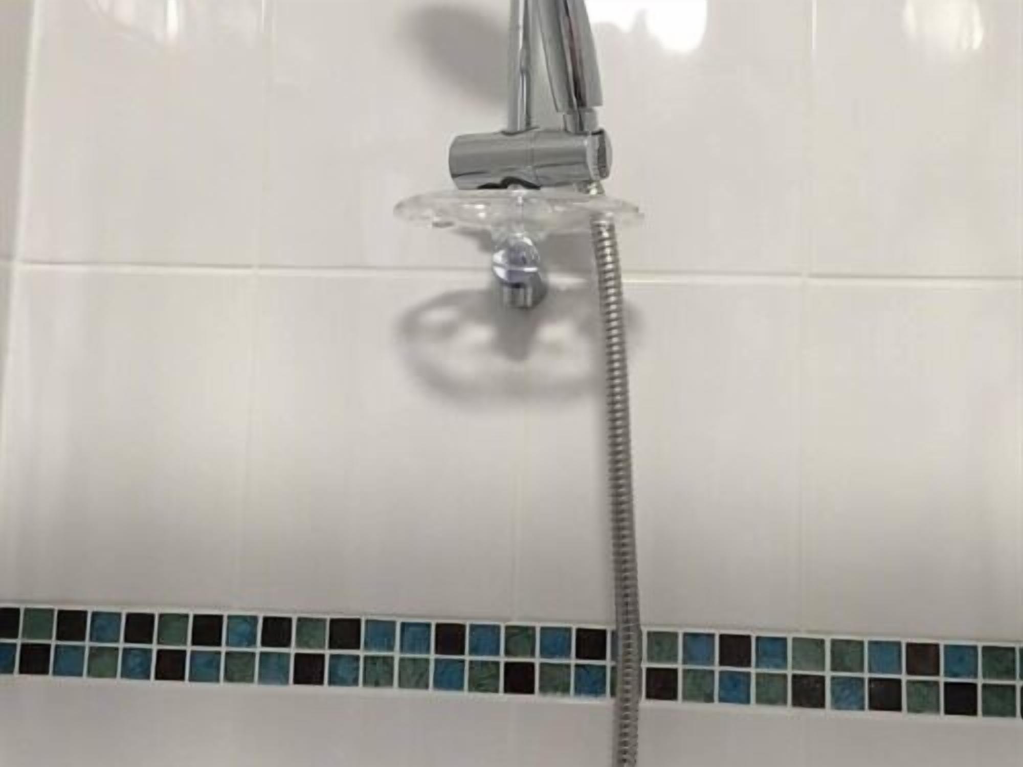 A shower with a chrome faucet and a handheld showerhead.