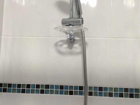 Una ducha con grifo de cromo y cabezal de ducha de mano.