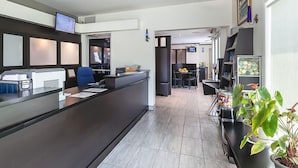 Una moderna área de recepción con un mostrador oscuro, una silla azul y un televisor de pantalla plana montado en la pared.
