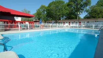 A swimming pool with a white fence, red awning, and a lifebuoy.