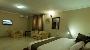 Una habitación de hotel con cama, sofá, televisor y espejo.