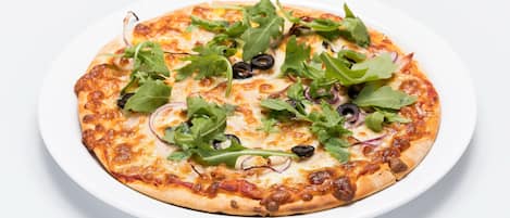 Eine Pizza mit Belag auf einem weißen Teller.