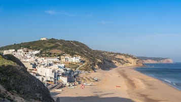 Un pueblo costero con edificios en una colina, una playa de arena y el mar.