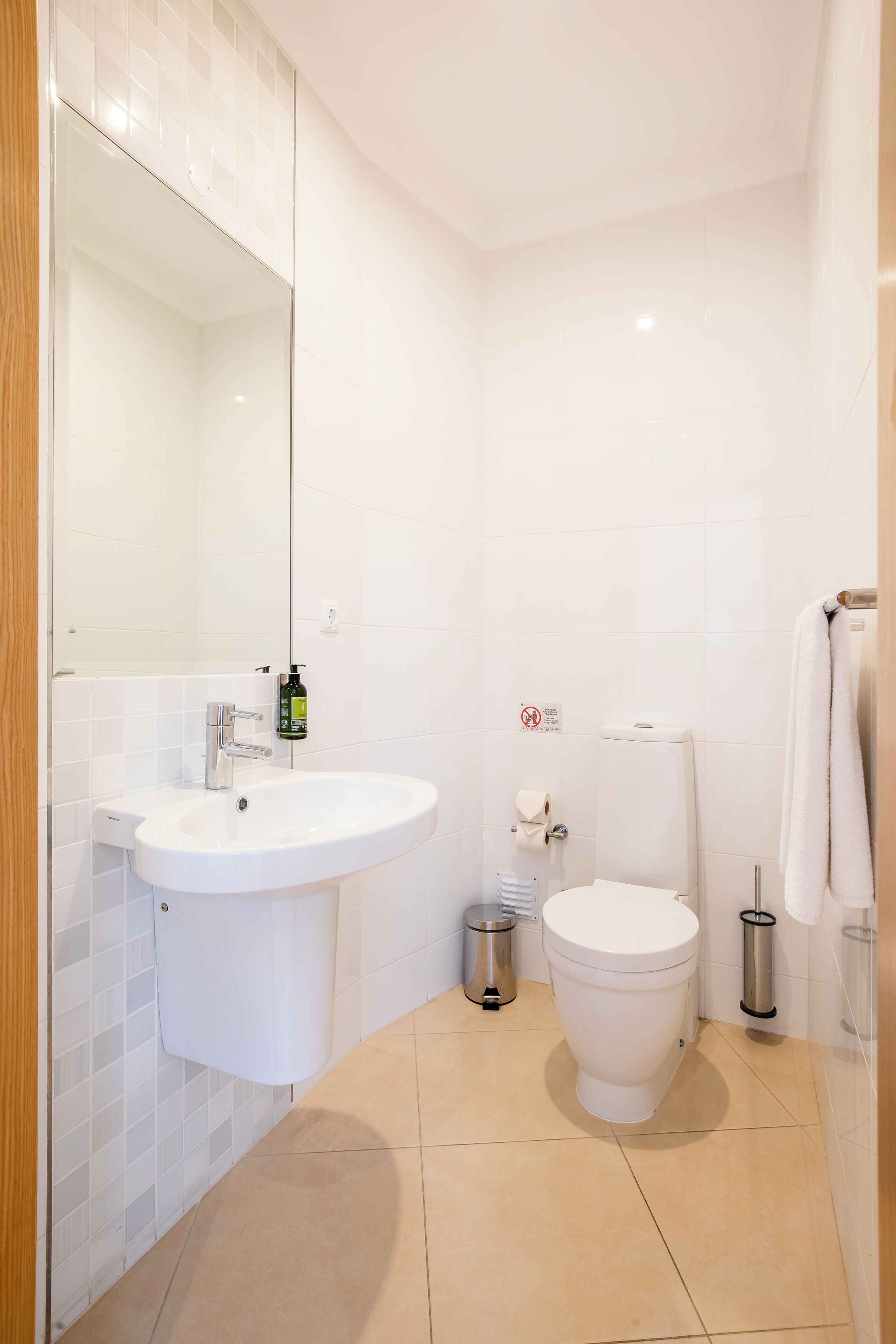 A modern bathroom with a white sink, toilet, and mirror.