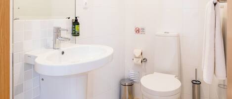 A modern bathroom with a white sink, toilet, and mirror.