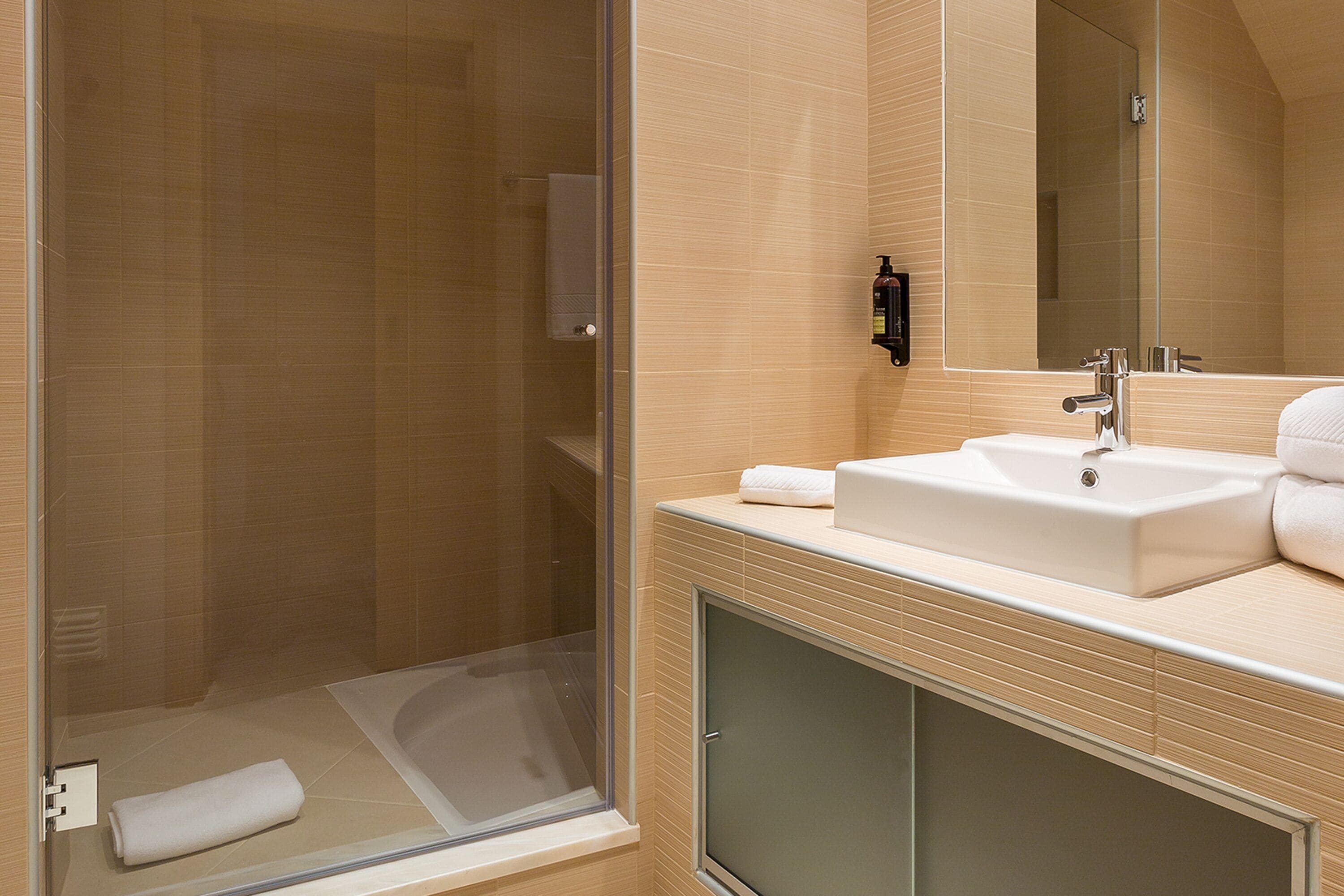 Ein modernes Badezimmer mit Duschkabine aus Glas, einem Waschbecken und einem Spiegel.