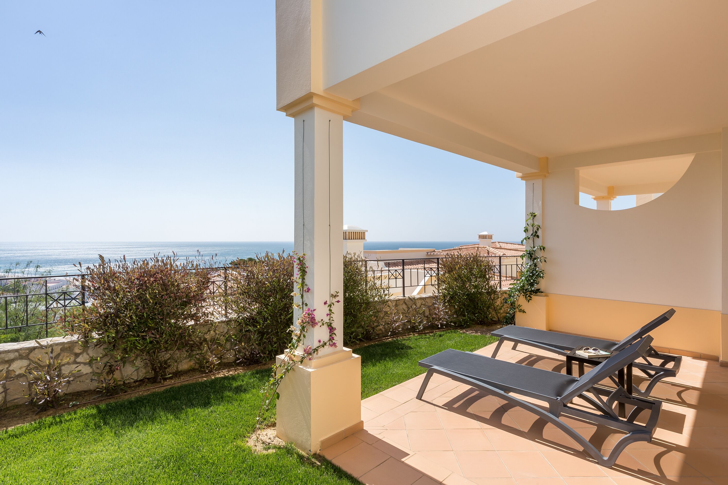 Una terraza con dos tumbonas, un muro de piedra y vistas al mar.